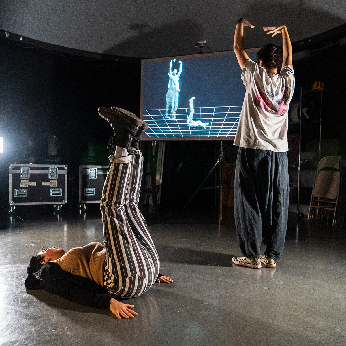 two students pose as their bodies are projected on to a screen in wireframes 